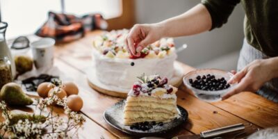 Frau garniert eine Torte mit frischen Beeren.