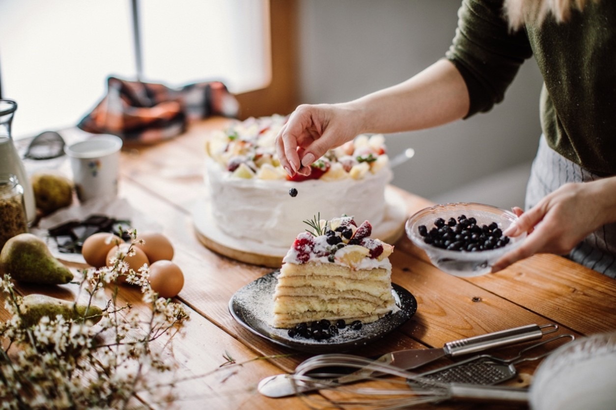 Frau garniert eine Torte mit frischen Beeren.